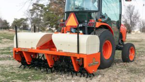 Field work using a New Land Pride CA25 Series Core Aerator attachment mounted on the back of a tractor.