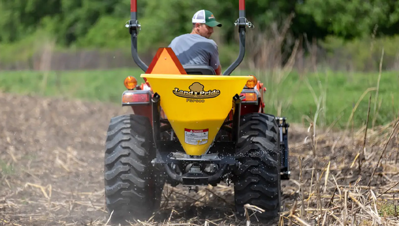 New Land Pride FSP Series Spreader attached to a tractor seeding a plot of land.