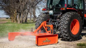 Person driving a Kubota tractor with a Land Pride GS15 Series Grading Scrapers attachment.