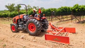 Person driving a Kubota tractor with a Land Pride GS25 Series Grading Scrapers attachment.