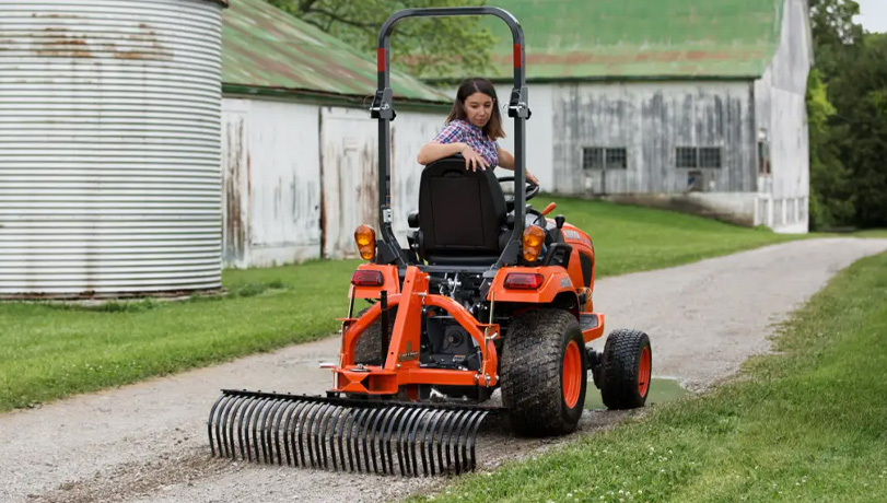 Land Pride LR05 Series Landscape Rake attached to the back of a Kubota tractor on a dirt path.