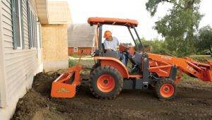 Construction professional using a Land Pride MR15 Box Scraper attachment on a Kubota tractor.