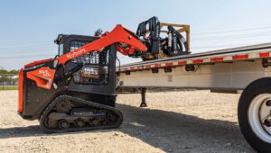 New Land Pride PFL Series Pallet Forks lifting heavy equipment onto a flatbed truck.