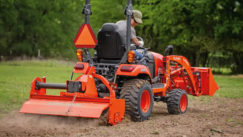 Land Pride RTR12 Series Rotary Tiller attached to the back of a Kubota tractor tilling a field.