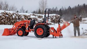 Worker using a Land Pride WC1503 Wood Chipper attached to a Kubota tractor grinding down a tree branch.
