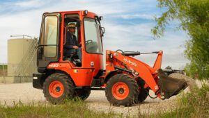 Person driving a Kubota R430 Wheel Loader emptying gravel onto a path or work area.