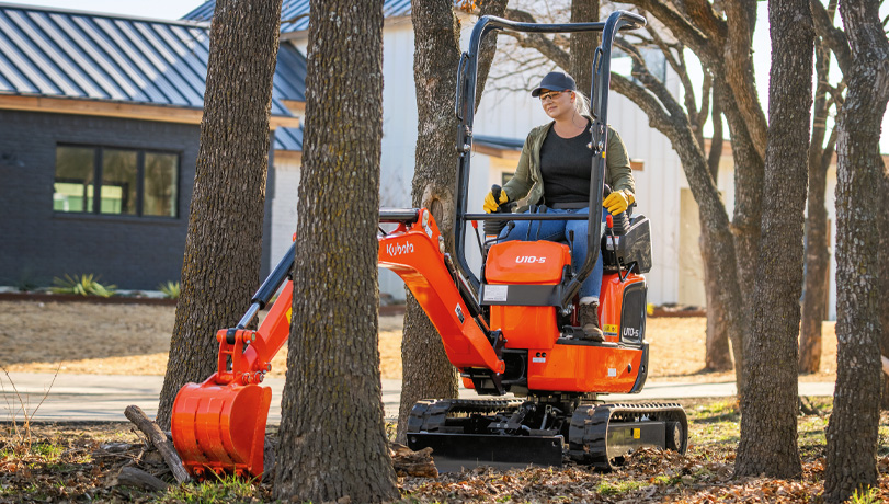 Woman in a black shirt and baseball cap clearing land with a Kubota U10-5 Excavator.
