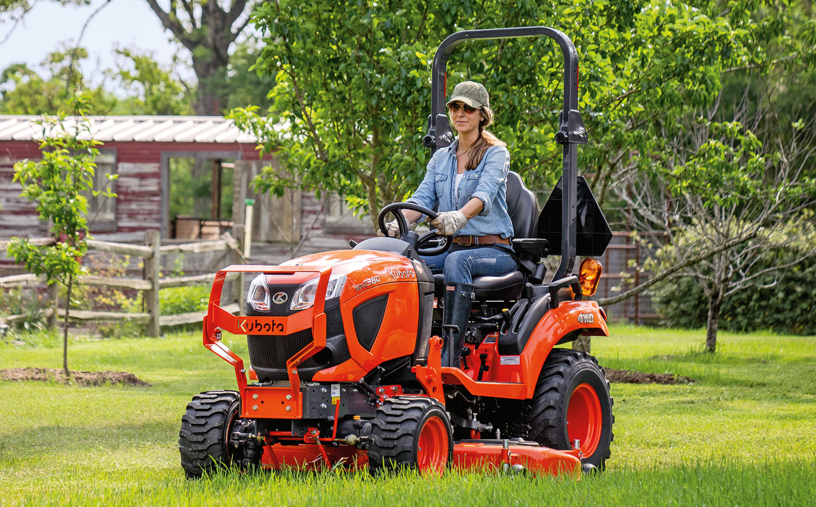 L-Series Kubota tractor in a green field on a sunny sky.