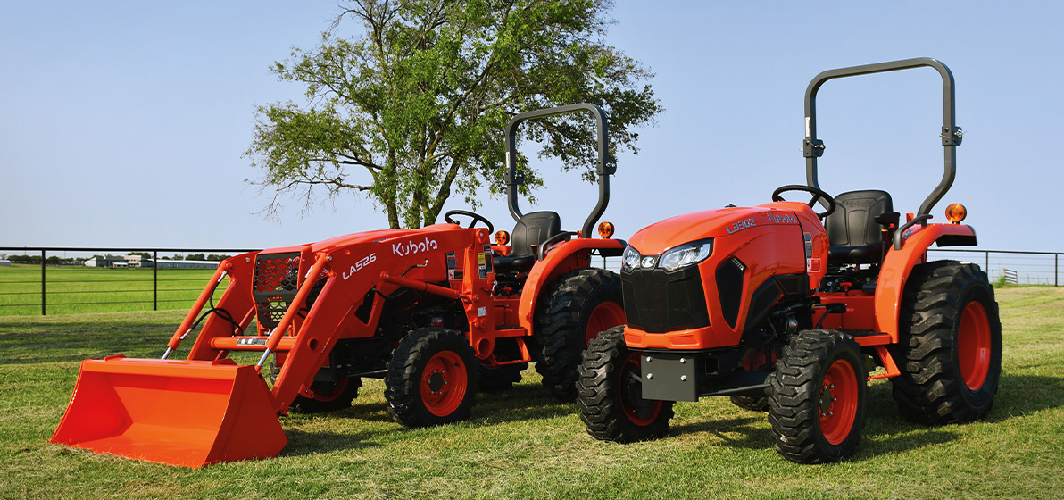 Two Kubota tractors in a green field.