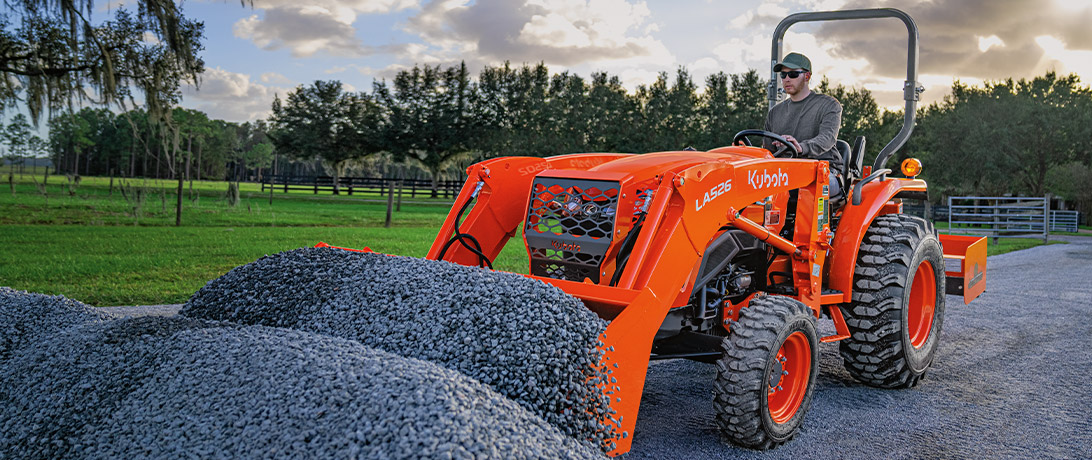Man driving an L02 Series tractor with a front-end loader.
