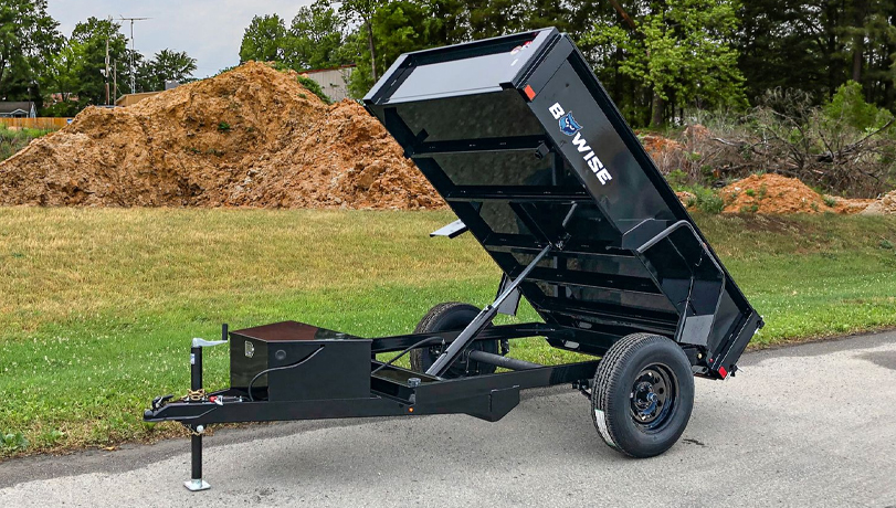 BWise Dump Trailer out in a field on top of concrete.