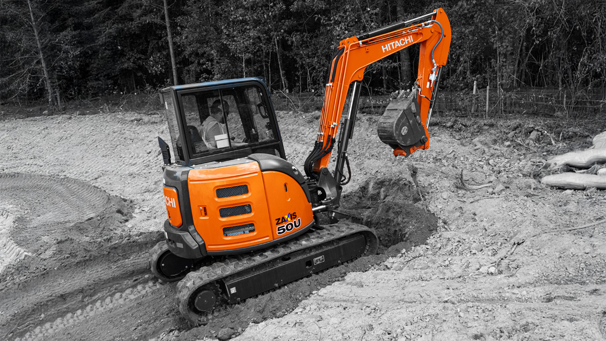 Tractor in a snowy field in front of a Christmas tree.