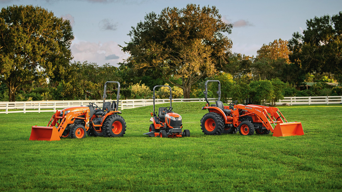 Multiple Kubota tractors in a green pasture.